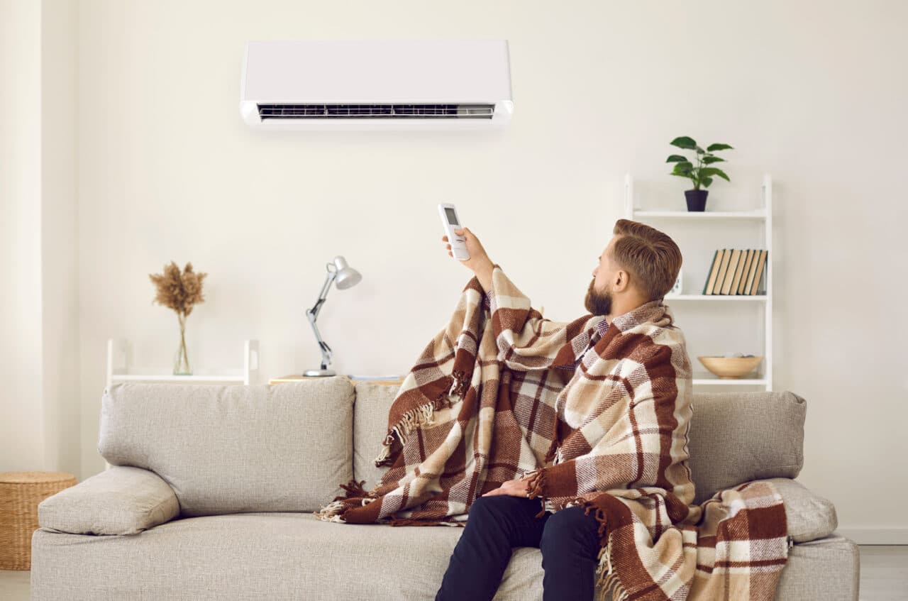 Man having problem with his air conditioning system and freezing in his cold apartment